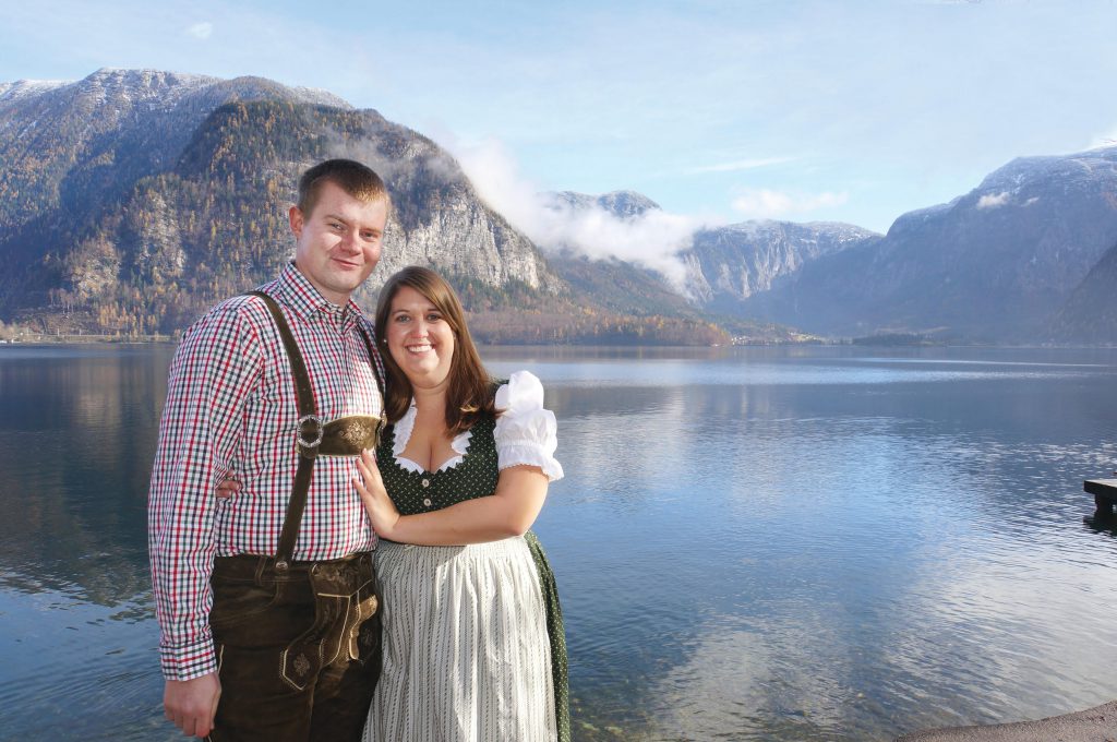Emily with husband wearing traditional Austrian dress in front of landscape
